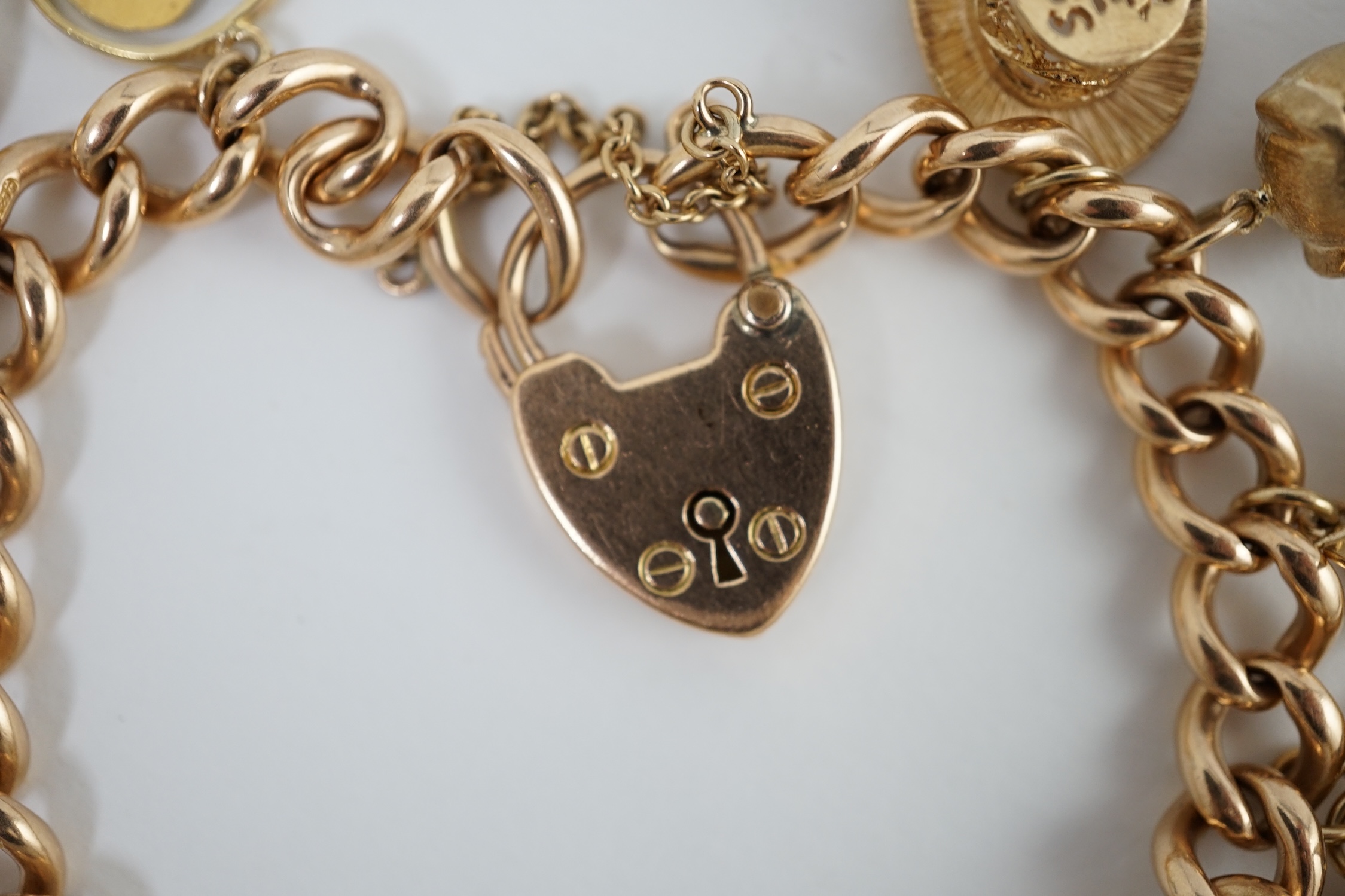 An early 20th century 15ct gold curb link charm bracelet